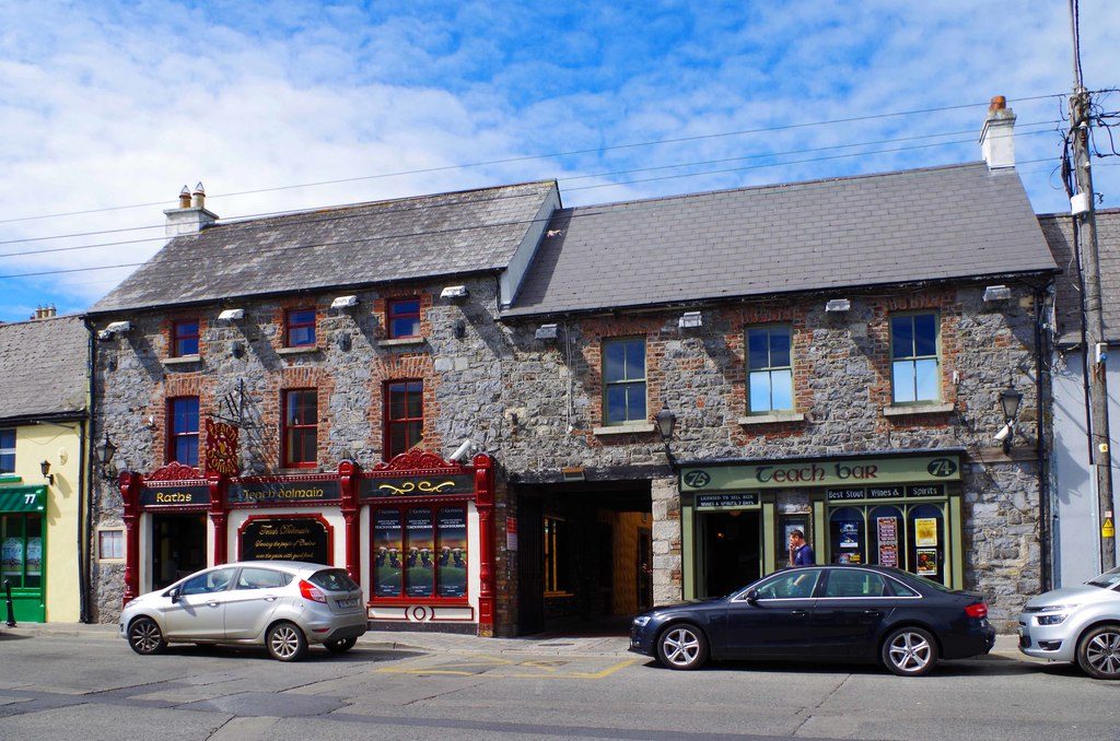 Teach Dolmain on Tullow Street: a stone-fronted building with a red and green shopfront